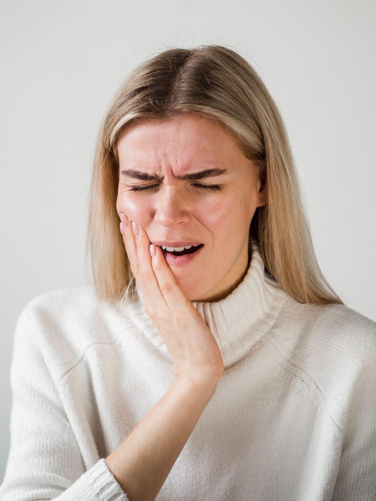 woman holding her jaw in pain