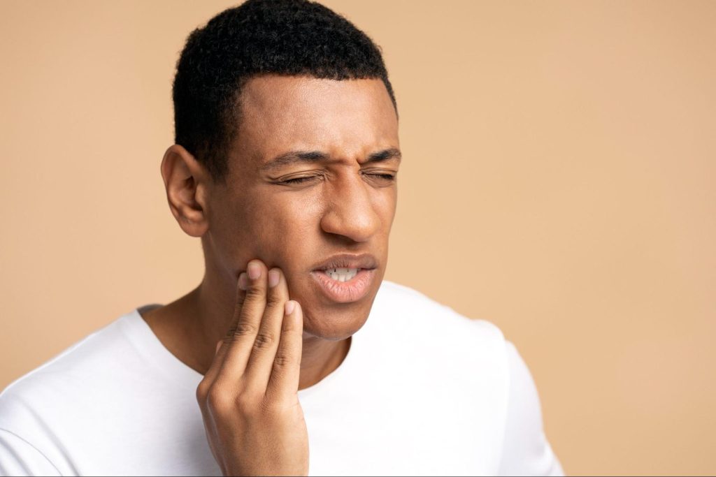 man with tooth pain touching his cheek