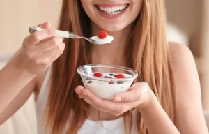 woman smiling eating a yoghurt bowl with fruits