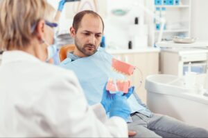 dentist showing a patient a dental tooth prop